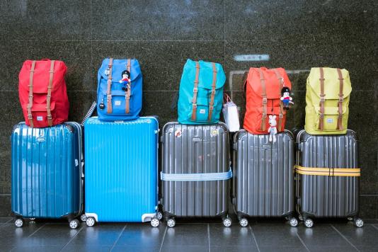 A group of suitcases with backpacks on top