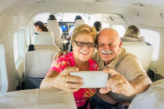An older couple taking a selfie on a plane