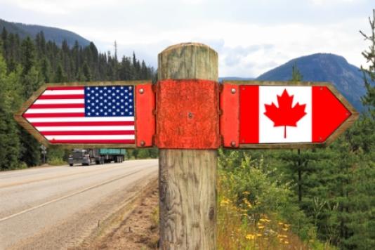 A wooden pole indicating the USA to the left and Canada to the right
